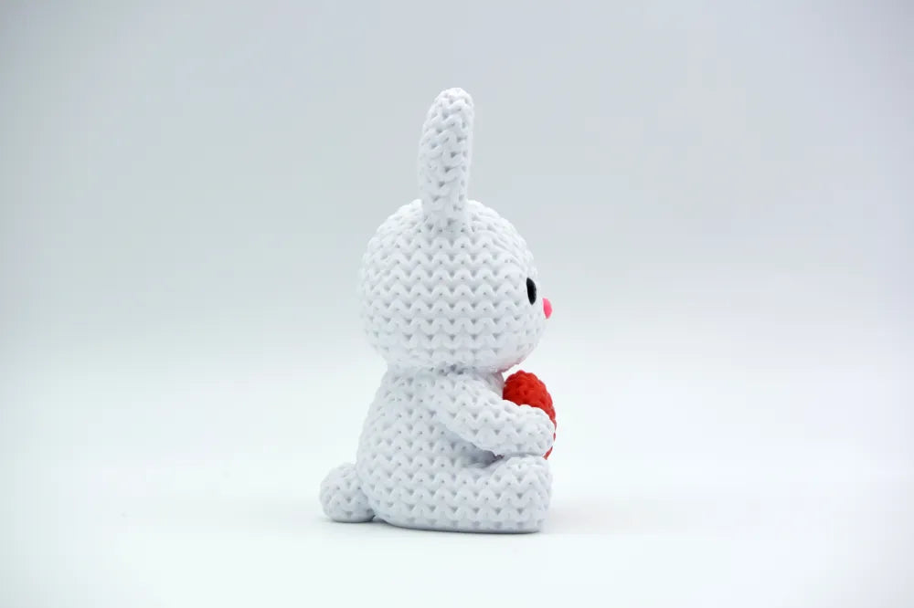 White coloured knitted textured 3D printed Bunny with heart figure/ key tag on a white background facing sideways