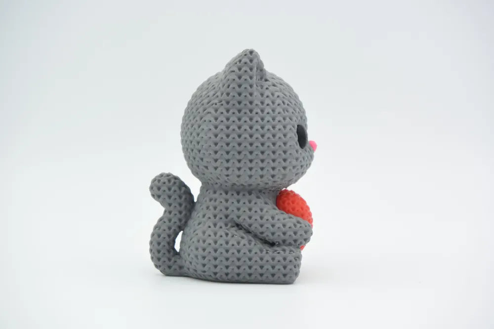 Grey coloured knitted textured 3D printed Cat with heart figure/ key tag on a white background facing side ways