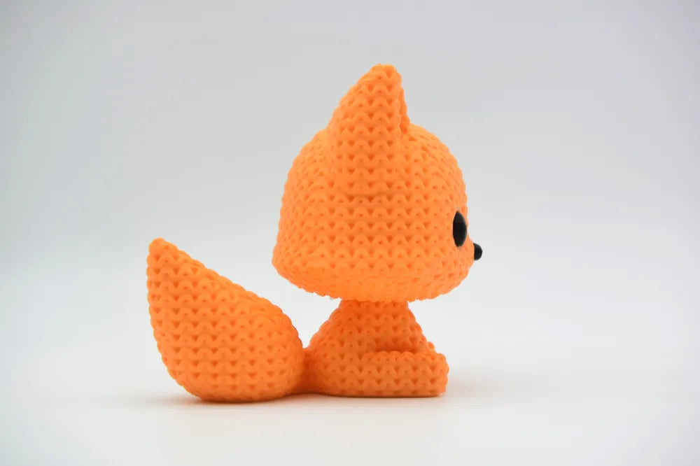 Orange knitted textured 3D printed fox figure/ key tag on a white background facing side ways