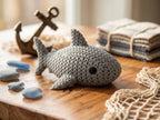 Knitted textured 3D printed shark figure/ key tag on a wooden surface with decorative items.