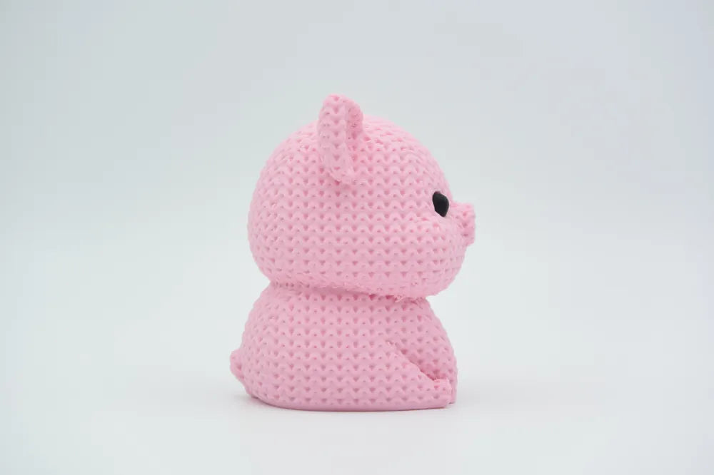Pink knitted textured 3D printed pig figure/ key tag on a white background facing side ways