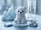 Knitted textured 3D printed polar bear Figure/ key tag on a icy surface with ice crystals and blurred trees in the background