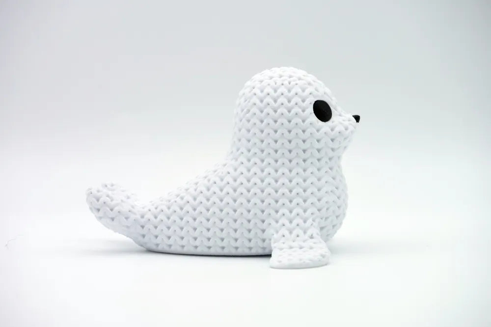 White knitted textured 3D printed seal figure/ key tag on a white background facing side ways
