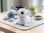 knitted textured 3D printed seal figure/ key tag on a wooden table with yarn and tools.